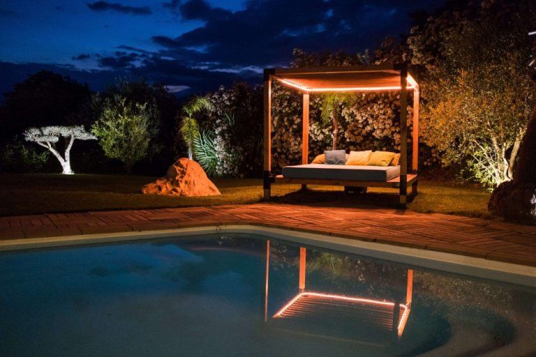 La piscine et le lit balinais éclairés à la nuit tombée